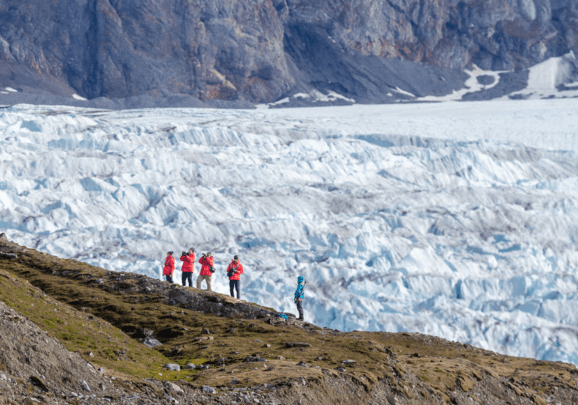 Gäste der Kreuzfahrt stehen oberhalb eines Gletschers in Spitzbergen und machen Fotos